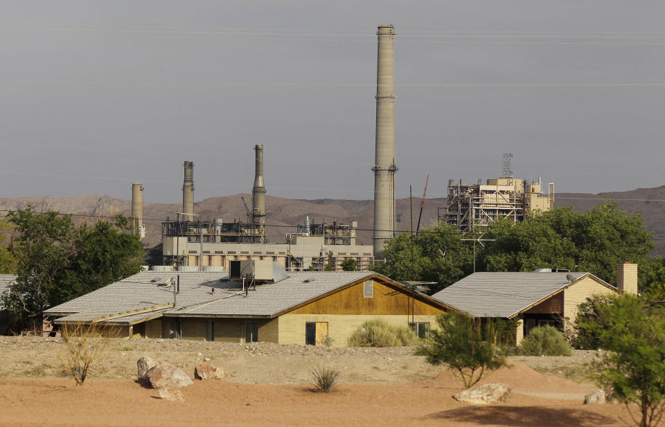 In this Monday, May 14, 2012, photo, the Reid-Gardner power station is seen just beyond homes on the Moapa Indian Reservation, in Moapa, Nev. Across the country, a disproportionate number of power plants operate near Indian tribal lands. Some tribes embrace the plants, which provide jobs and tax dollars to their communities. But a small group have begun to protest the plants in recent years, asking that they be closed down. (AP Photo/Julie Jacobson)