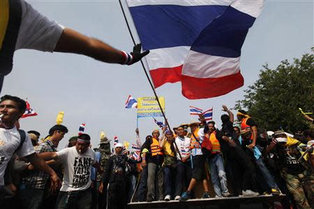 Anti-government protesters celebrate on a front loader used to knock down a concrete barricade outside the Government House in Bangkok December 9, 2013. REUTERS/Kerek Wongsa