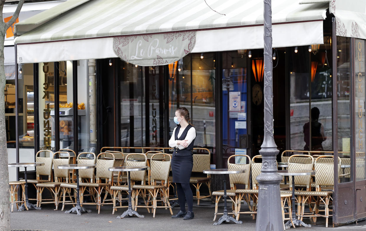 PARIS, FRANCE - OCTOBER 22: A waitress wearing a protective face mask waits for customers in front of an empty restaurant terrace near Notre-Dame Cathedral during the coronavirus outbreak on October 22, 2020 in Paris, France. In the absence of tourists due to the coronavirus pandemic (COVID 19) and measures taken by the French government to curb the disease, many bars, restaurants and souvenir shops are empty in tourist sites in the capital. (Photo by Chesnot/Getty Images)