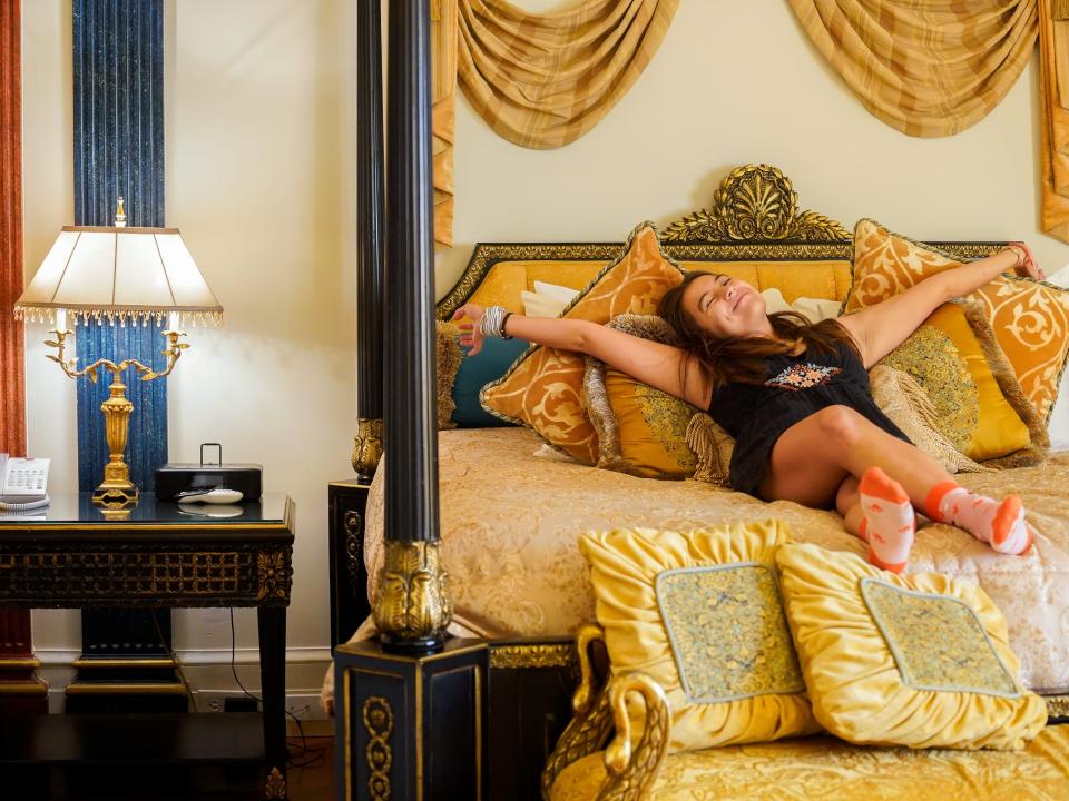 The author stretches out on the bed in the Aurora Suite in the former Versace Mansion