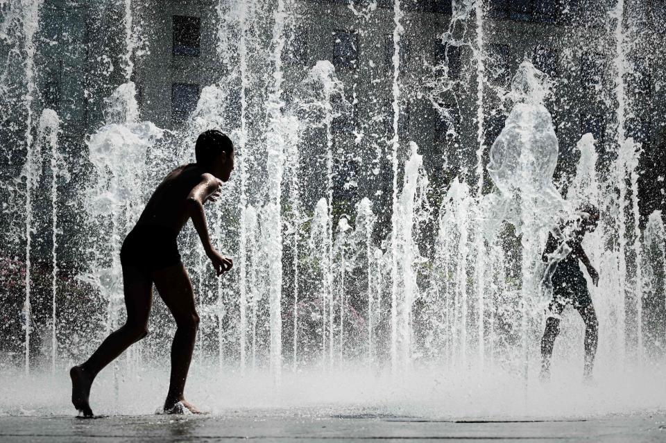 Children play at the dancing fountains of the Andre Citroen park in Paris on July 23, 2019.