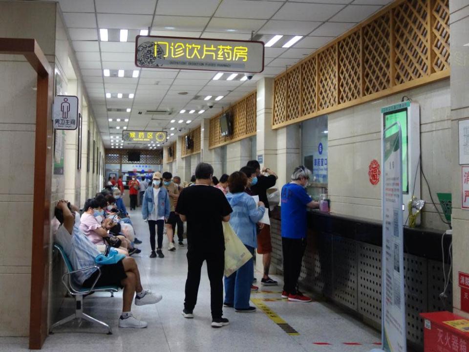 Hospital corridor with people seated and standing as they wait for medical attention