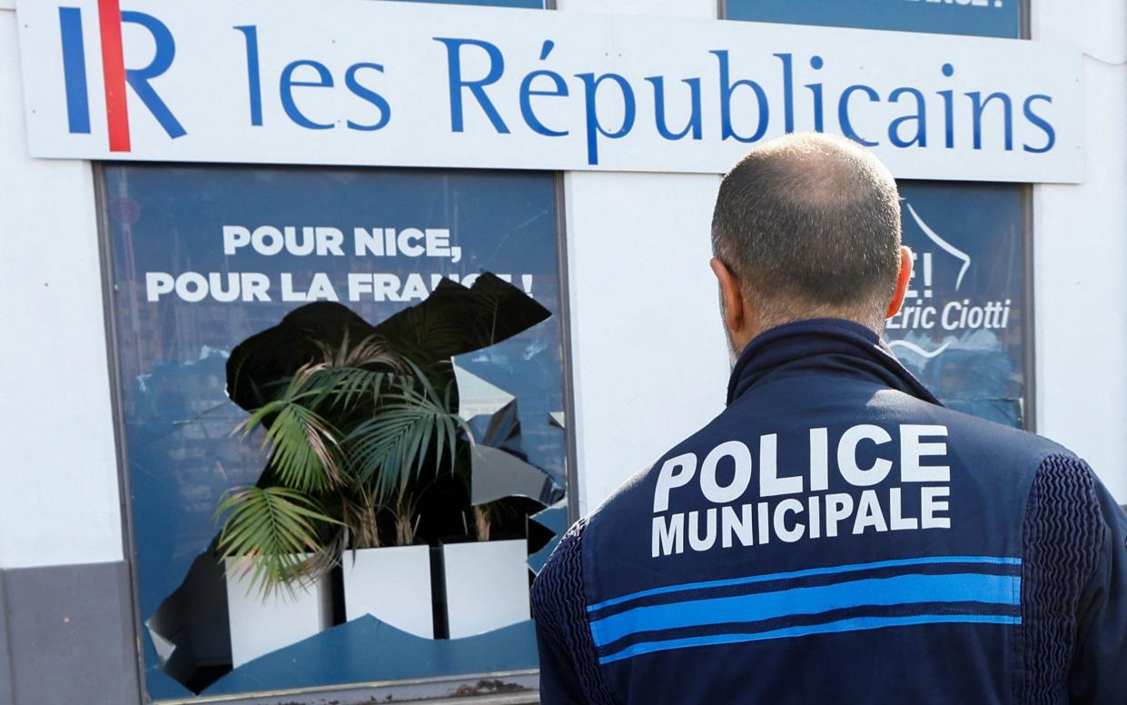 A policeman surveys Eric Ciotti’s vandalised office front. Mr Ciotti is head of the Republican party - Eric Gaillard/Reuters