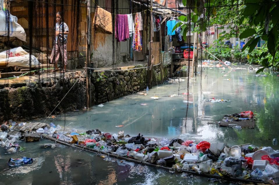 A child walks next to a polluted river in Jakarta
