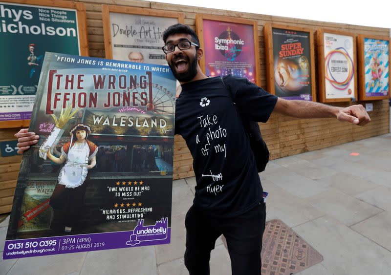 FILE PHOTO: A man holding a poster is seen in front of flyers advertising shows at the Fringe in Edinburgh