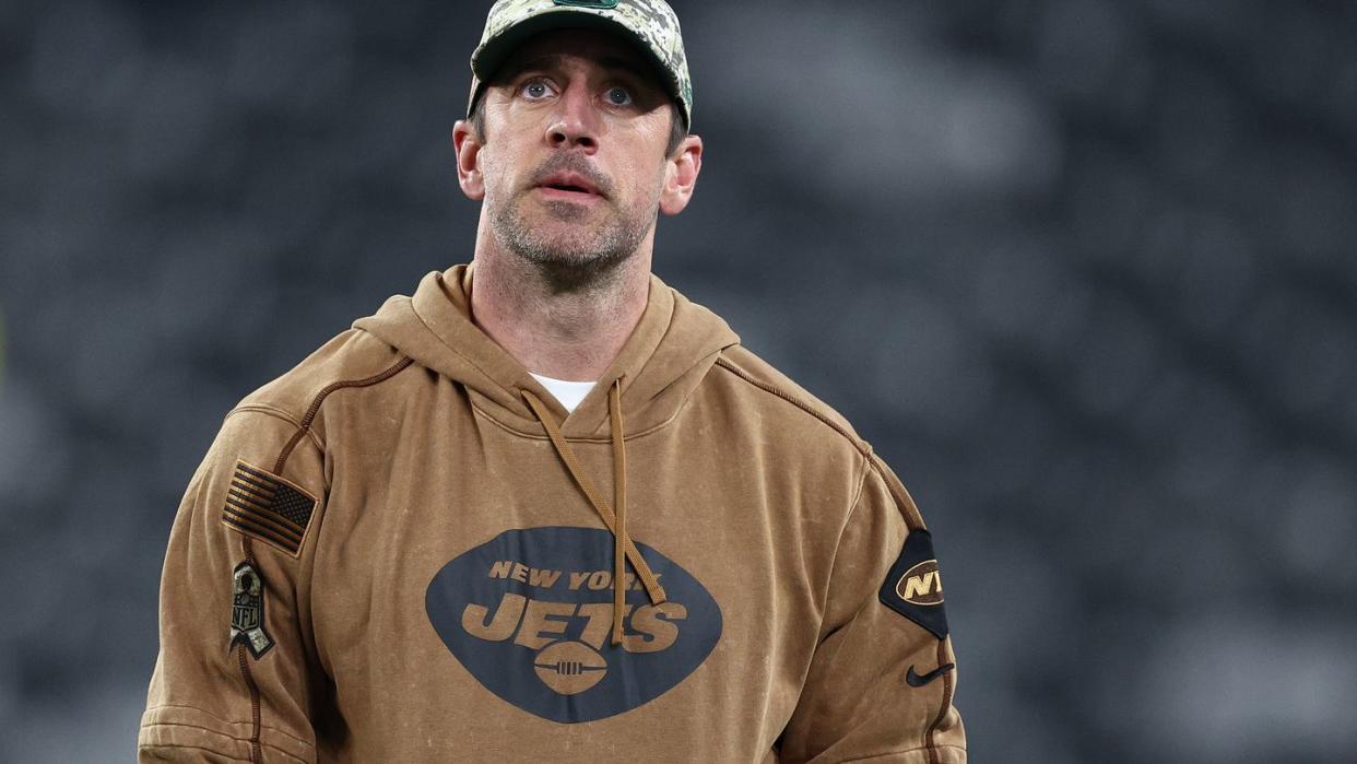 aaron rodgers wearing a camouflage hat and looking upward