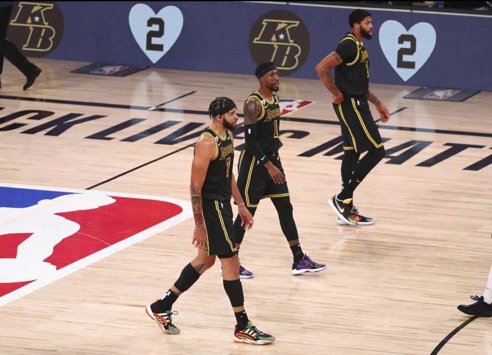 FILE - In this Aug. 24, 2020, file photo, Los Angeles Lakers center JaVale McGee (7), guard Kentavious Caldwell-Pope (1) and forward Anthony Davis (3) walk in front of the boards remembering late Los Angeles Lakers player Kobe Bryant in the first half of Game 4 of an NBA basketball first-round playoff series against the Portland Trail Blazers in Lake Buena Vista, Fla. The jerseys will be hanging in their lockers when the Los Angeles Lakers arrive for Game 2 of the NBA Finals on Friday night, Oct. 2. Black jerseys, trimmed in gold, a snakeskin print on the exterior to make it further unique.T hey are the Black Mamba jerseys. Designed by Kobe Bryant — and now worn for Kobe Bryant. “We never want to lose in these jerseys,” Lakers forward Anthony Davis said.(Kim Klement/Pool Photo via AP, File)
