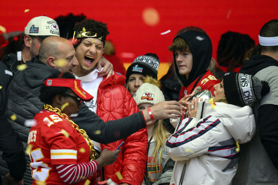 Brittany Mahomes, right, keeps the silver football her husband, Patrick Mahomes, laughing, was carrying, away from Kansas City Chiefs quarterback coach Matt Nagy left, during the Kansas City Chiefs' victory celebration and parade in Kansas City, Mo., Wednesday, Feb. 15, 2023. The Chiefs defeated the Philadelphia Eagles in the NFL Super Bowl 57 football game. (AP Photo/Reed Hoffmann)