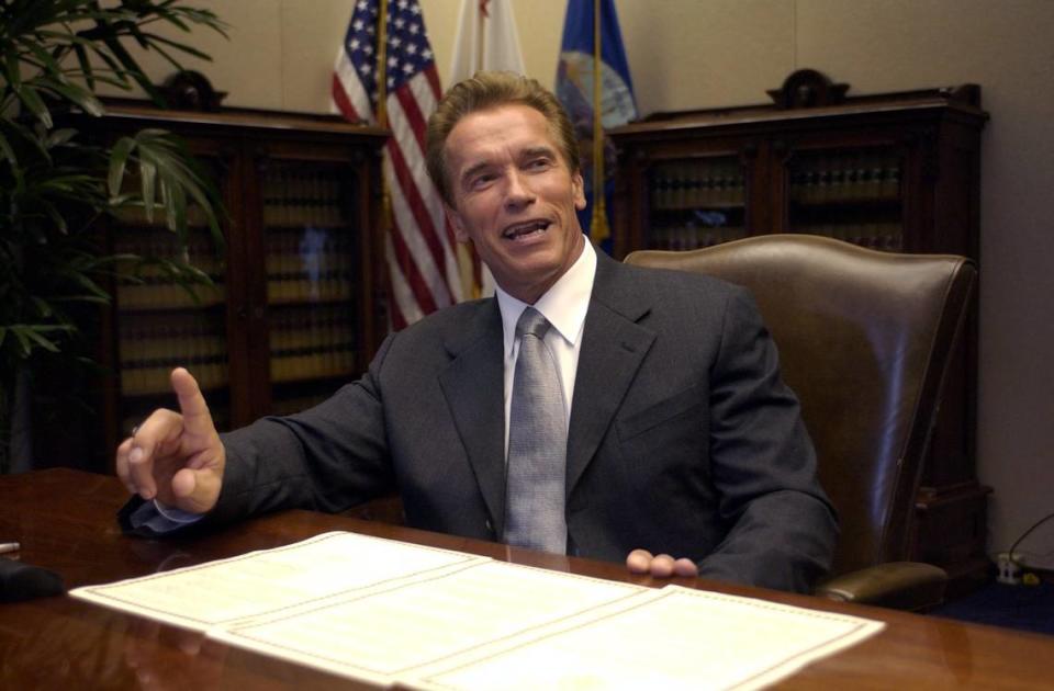 Gov. Arnold Schwarzenegger smiles before he signs an executive order to repeal the car tax minutes after taking the oath of office as California’s 38th governor on the steps of the state Capitol on Monday, Nov. 17, 2003.