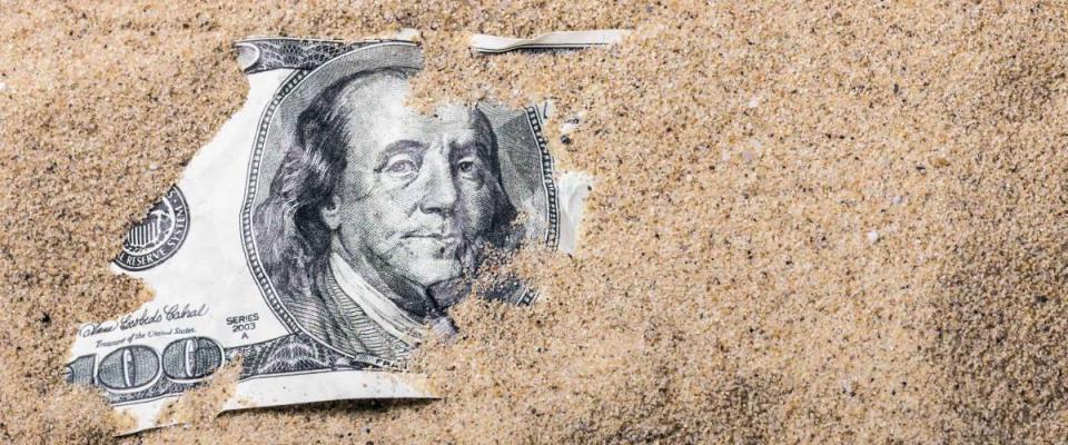 100 dollar bill buried in the sand