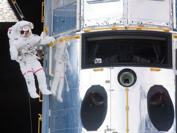 NASA astronaut John Grunsfeld hanging onto the Hubble Space Telescope.