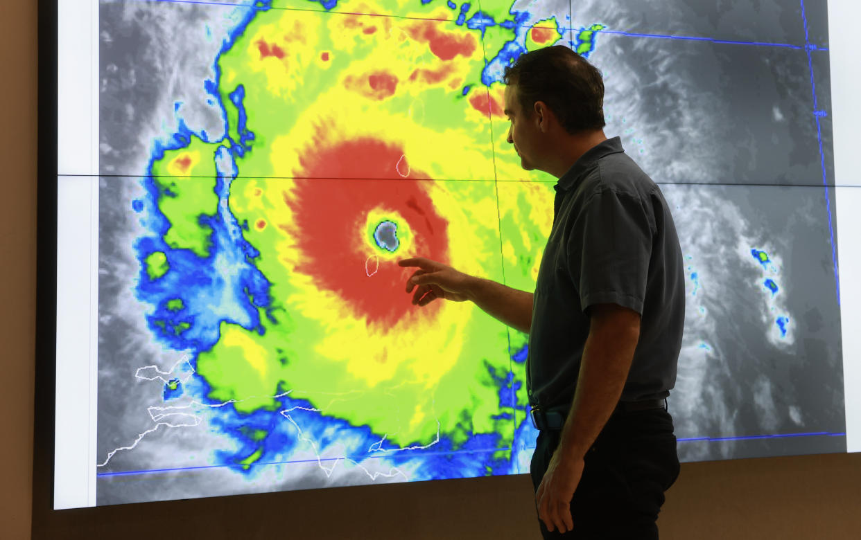 John Cangialosi, senior hurricane specialist at the National Hurricane Center, inspects a satellite image on a large screen in front of him.