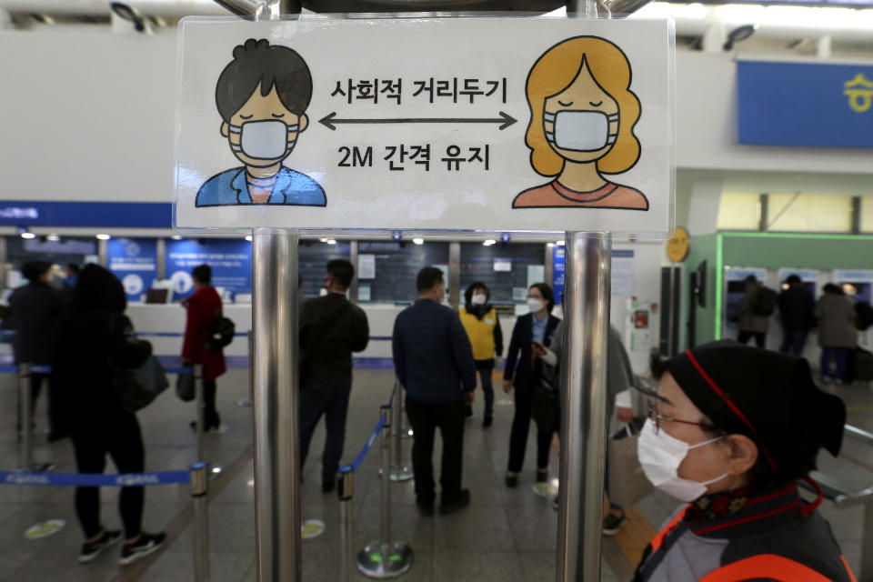 A social distancing sign is seen as people wait to buy tickets at the Seoul Railway Station in Seoul, South Korea, Friday, Nov. 13, 2020. South Korea has reported its biggest daily jump in COVID-19 cases in 70 days as the government began fining people who fail to wear masks in public. The Korean letters read "Social distance and keep 2 meter away."(AP Photo/Ahn Young-joon)