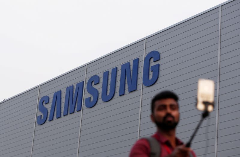 FILE PHOTO: A journalist uses a mobile phone as he works outside the Samsung Electronics smartphone manufacturing facility in Noida