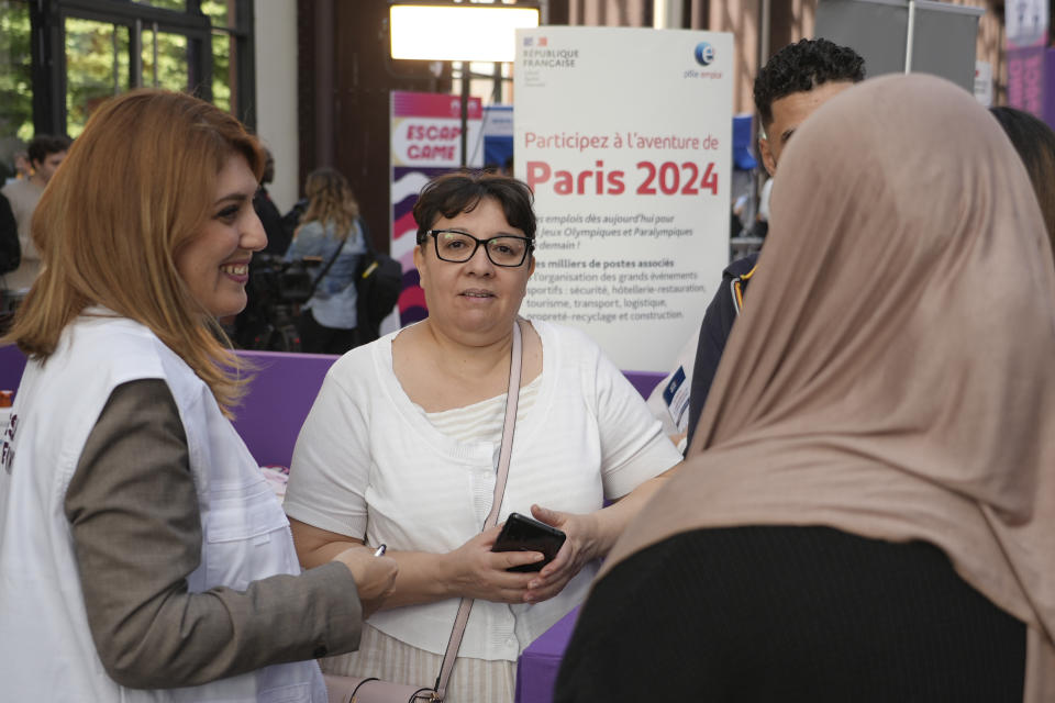 People ask for information on job possibilities Tuesday, Sept. 26, 2023 in Saint-Denis, a northern suburb of Paris. Paris Olympics organizers and their partners organized a giant job fair meant to help filling about 16,000 vacancies in key sectors including catering, security, transport and cleaning. About 50 companies are recruiting to be able to welcome next year millions of spectators and 14,500 athletes. (AP Photo/Nicolas Garriga)