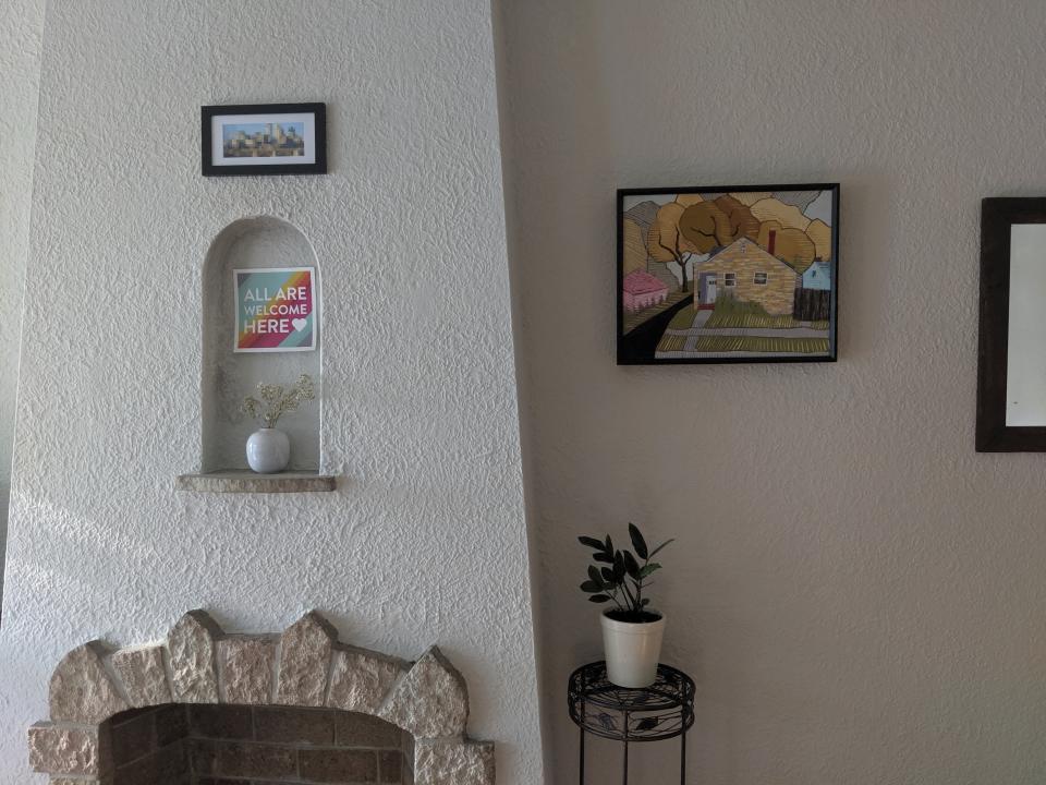 This July 29, 2019 photo provided by Holly Oehme shows borrowed art hanging on the wall of her home in Minneapolis. Oehme loves borrowing art from the Minneapolis Art Lending Library and has a dedicated space for the pieces. The art of the house at right is by Robert Nicholl and titled "527 24th St. (blue)", 2011. (Holly Oehme via AP)
