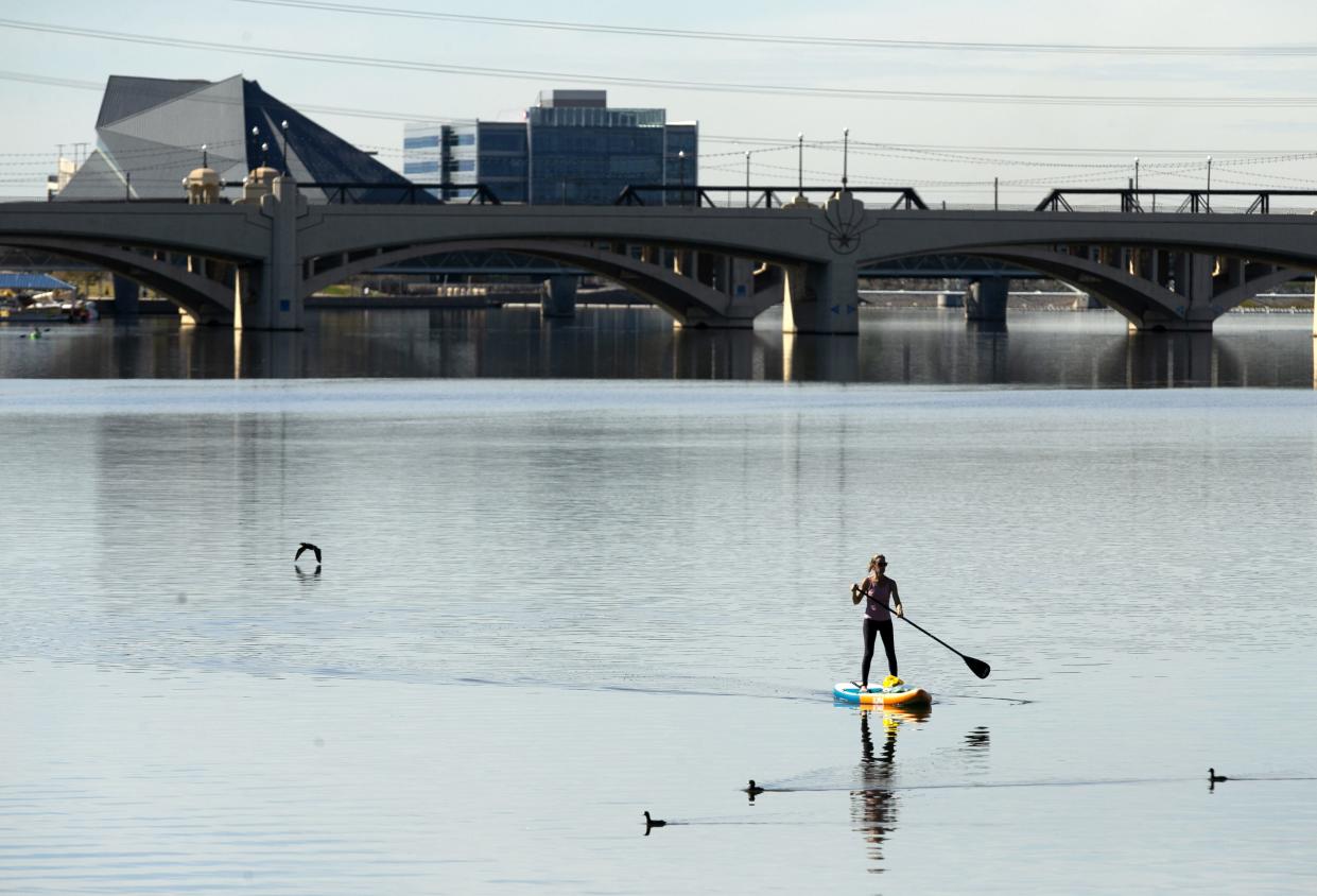 Jaime Burton of Chandler, Ariz., stand-up paddle boards at  Tempe Town Lake in Tempe, Ariz., on Tuesday, February 2, 2021. According to the National Weather Service temperatures reached 80 degrees in Phoenix on Tuesday afternoon.