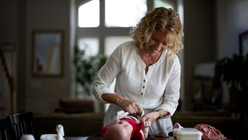 Cindy Davis unswaddles her 9-week-old granddaughter Indy while babysitting her at home in Cedar Hills on Tuesday, Aug. 15, 2023.