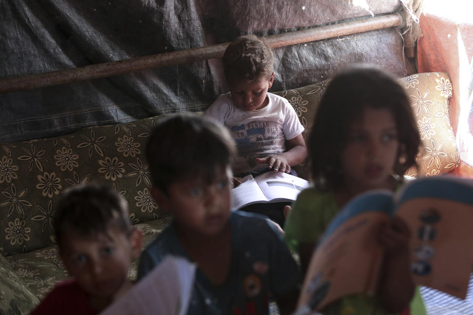 Syrian children read books in a refugee camp near Amman, Jordan, on Monday, June 5, 2023. (AP Photo/Raad Adayleh)