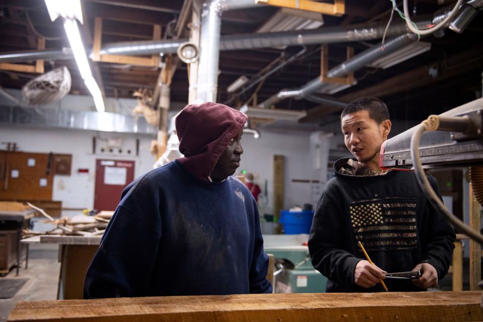 Zhan Cobb, Soteria graduate and current project manager at Soteria Community Development Corporation, 28, right, helps Mike Gambrell, 59, program participant, learn how to cut wooden beams in the shop on Wednesday, Dec. 13, 2023.