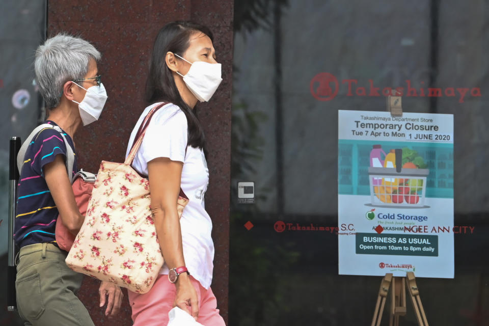 People, wearing face masks as a preventive measure against the spread of the COVID-19 novel coronavirus, walk past a closed retail mall along the Orchard Road shopping belt in Singapore on May 6, 2020. (Photo by Roslan RAHMAN / AFP) (Photo by ROSLAN RAHMAN/AFP via Getty Images)