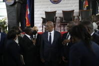 New Prime Minister Ariel Henry, center, talks with former interim Prime Minister Claude Joseph as they stand surrounded by Henry's cabinet after his appointment in Port-au-Prince, Haiti, Tuesday, July 20, 2021, weeks after the assassination of President Jovenel Moise at his home. (AP Photo/Joseph Odelyn)