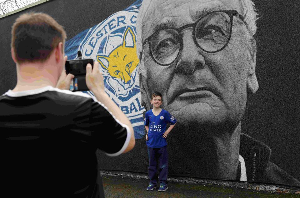 A boy poses for a photograph in front of a mural of Leicester City manager Claudio Ranieri, by Artist Richard Wilson, ahead of Leicester City's away soccer match against Manchester United, Leicester, Britain May 1, 2016 REUTERS/Eddie Keogh