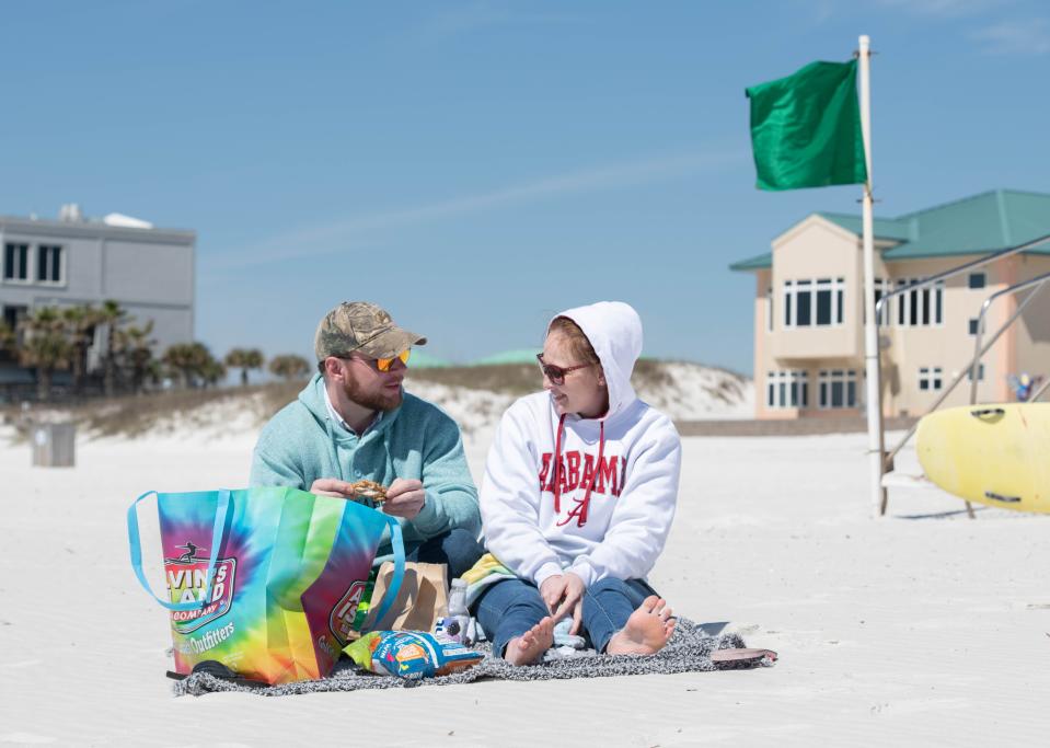 Michael Bass, left, and Valerie King, of Birmingham, Alabama, try to stay warm while enjoying Pensacola Beach on Monday, March 20, 2023.