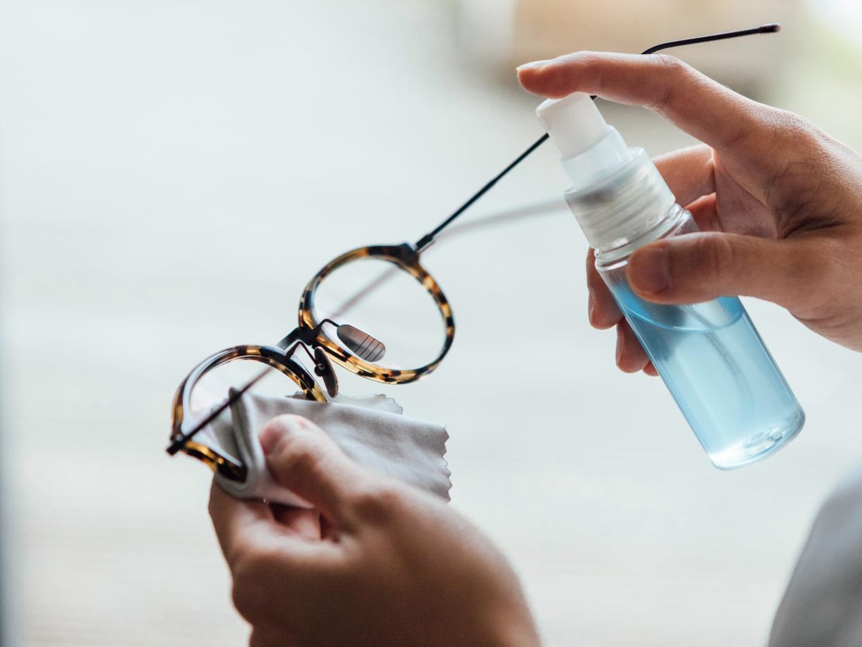 Close up shot of woman cleaning eyewear surface with sanitising spray