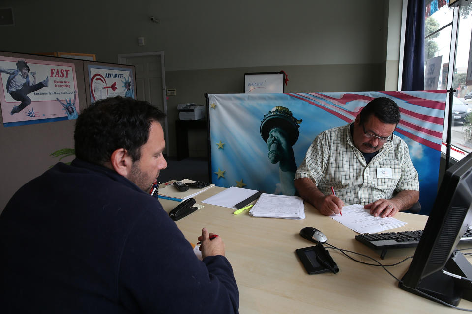 El preparador de impuestos Robert Romero (R) ayuda a un cliente a preparar sus impuestos sobre la renta en Liberty Tax Service en San Francisco, California. Los preparadores de impuestos están ayudando a los contribuyentes de última hora antes de la fecha límite del 18 de abril para presentar impuestos estatales y federales sobre la renta. (Crédito: Justin Sullivan, Getty Images)