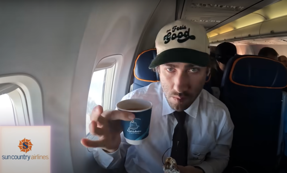 Decker enjoys a drink while flying on Sun Country Airlines. YouTube/ Airrack