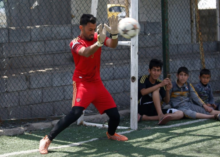 A goalkeeper attempts to stop a shot during a football match in eastern Mosul's al-Salam neighbourhood