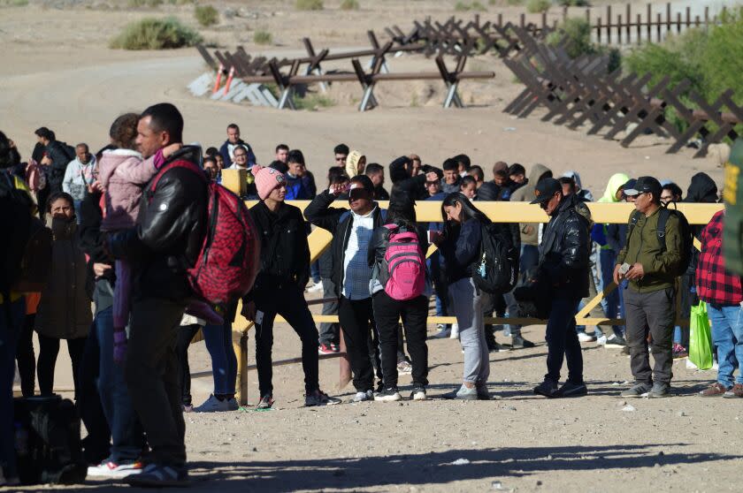 Dozens of immigrants from as far away as India and Africa wait to be processed by Customs and Border Protection officers along the border wall in Somerton, Arizona, on Friday, May 5, 2023.