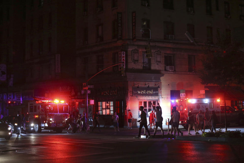 Pedestrians cross the street near emergency response vehicles at 50th Street and 8th Avenue during a power outage, Saturday, July 13, 2019, in New York. Authorities were scrambling to restore electricity to Manhattan following a power outage that knocked out Times Square's towering electronic screens and darkened marquees in the theater district and left businesses without electricity, elevators stuck and subway cars stalled. (AP Photo/Michael Owens)