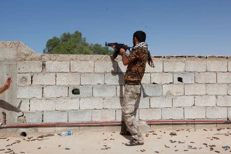 A fighter from forces aligned with Libya's new unity government fires a weapon from atop a house on an Islamic State position in the Zaafran area in Sirte June 30, 2016. REUTERS/Ismail Zitouny