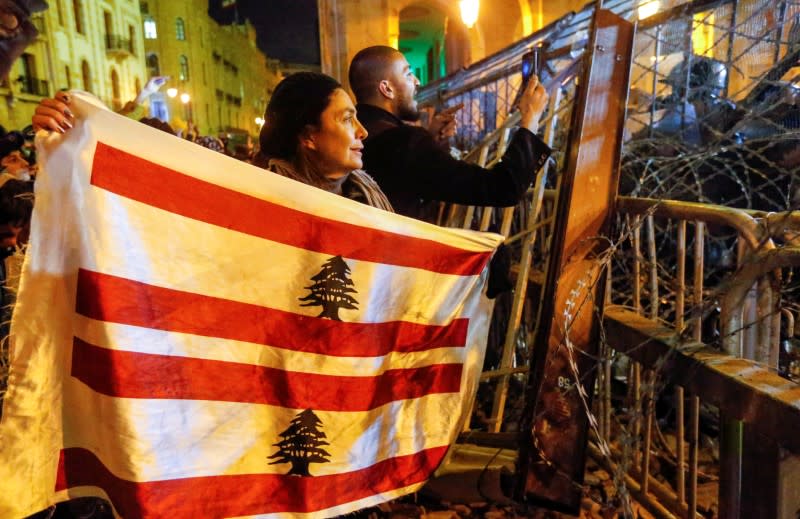 FILE PHOTO: A demonstrator holds the Lebanese flag during a protest against a ruling elite accused of steering Lebanon towards economic crisis in Beirut