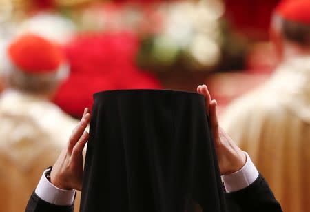 An Orthodox priest wears his cap as Pope Francis leads the Christmas night Mass in Saint Peter's Basilica at the Vatican December 24, 2016. REUTERS/Tony Gentile