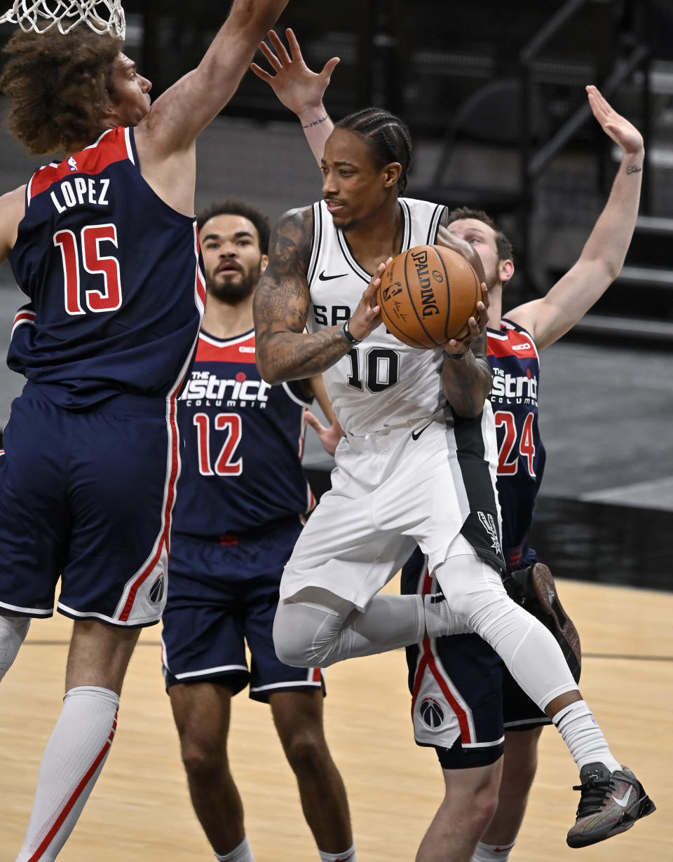 San Antonio Spurs' DeMar DeRozan (10) looks to pass as he is defended by Washington Wizards' Robin Lopez (15), Jerome Robinson (12) and Garrison Mathews during the first half of an NBA basketball game, Sunday, Jan. 24, 2021, in San Antonio. (AP Photo/Darren Abate)