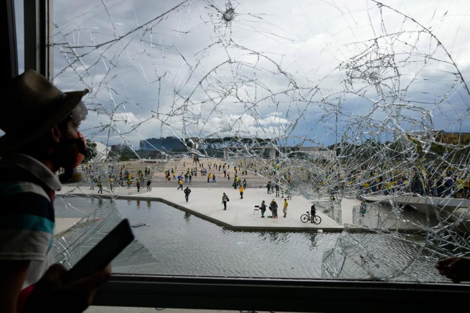 Mandatory Credit: Photo by Eraldo Peres/AP/Shutterstock (13702583ar) Protester, supporter of Brazil's former President Jair Bolsonaro, looks out from a shattered window of the Planalto Palace after he and many others stormed it, in Brasilia, Brazil, . Planalto is the official workplace of the president of Brazil Elections Protest, Brasilia, Brazil - 08 Jan 2023