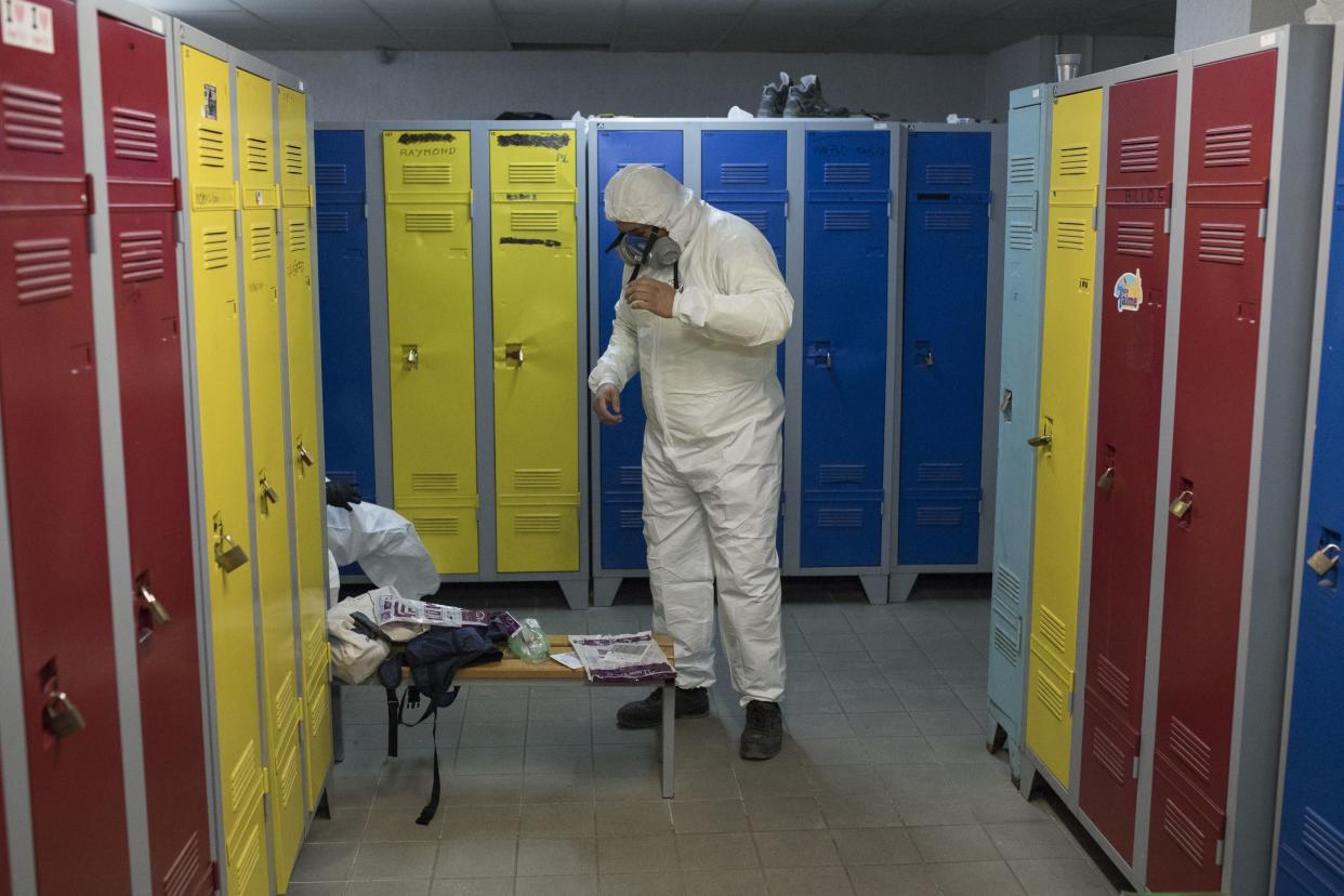 A worker puts on protective gear to spray disinfectant as a precautionary measure against coronavirus, during a nationwide confinement to control the spread of the virus, in Aubagne, southern France, on Tuesday, March 31, 2020.