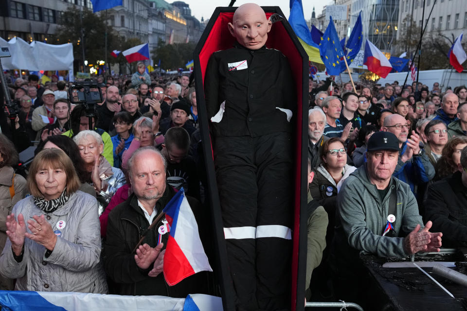 People clap their hands by a statue depicting Russian President Vladimir Putin, as tens of thousands of people gathered for an anti-war protest in Prague, Czech Republic, Sunday, Oct. 30, 2022. (AP Photo/Petr David Josek)