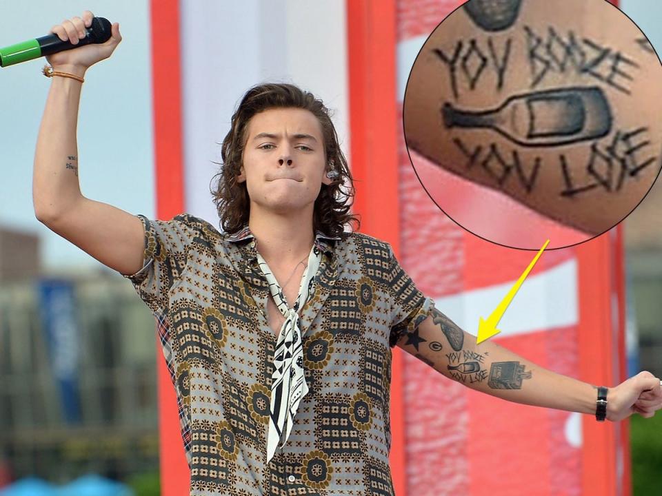 A yellow arrow pointing to a tattoo that reads "You booze, you lose" on Harry Styles' left forearm.