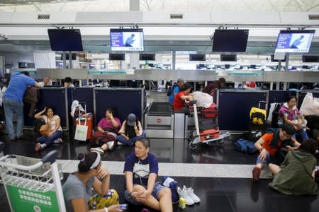 Passengers rest at the check-in counters after all flights were cancelled due to a protest inside the airport terminal in Hong Kong