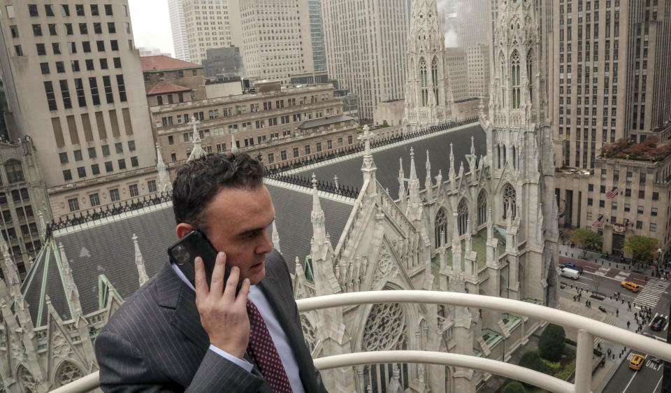 In this Tuesday, Oct. 29, 2019, photo, attorney Adam Slater takes a phone call on a patio outside his high-rise Manhattan office overlooking St. Patrick's Cathedral, in New York. Slater's firm is representing clients accusing the Roman Catholic Church of sexual abuse, a clientele that is rapidly growing after New York state opened its one-year window allowing sex abuse suits with no statute of limitations. (AP Photo/Bebeto Matthews)