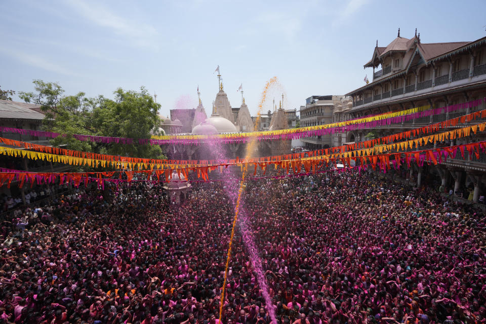 Devotees cheer as colored powder and water is sprayed on them during celebrations marking Holi at the Kalupur Swaminarayan temple in Ahmedabad, India, Sunday, March 24, 2024. (AP Photo/Ajit Solanki)