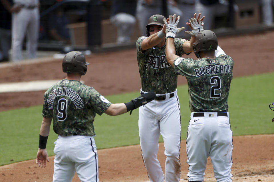 San Diego Padres' Matt Carpenter, center, celebrates with Xander Bogaerts, right, and Jake Cronenworth, left, after all scoring on a three-run double hit by Rougned Odor during the first inning of a baseball game against the Boston Red Sox, Sunday, May 21, 2023, in San Diego. (AP Photo/Brandon Sloter)