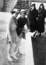 <p>British skater Cecilia Colledge (right) and German skater Viktoria Lindpaintner (left) on the rink in their Olympic outfits. Lindpaintner went with a matching knit shirt and skirt with a buttoned cardigan, while Colledge wore a pinstriped blazer, but both wore matching white hats. Hats are riskier to wear in competition today because skaters <a rel="nofollow noopener" href="http://www.cosmopolitan.com/style-beauty/fashion/a19764/ice-skating-costume-facts/" target="_blank" data-ylk="slk:receive a deduction;elm:context_link;itc:0;sec:content-canvas" class="link ">receive a deduction</a> if any part of their costume falls onto the ice.</p>