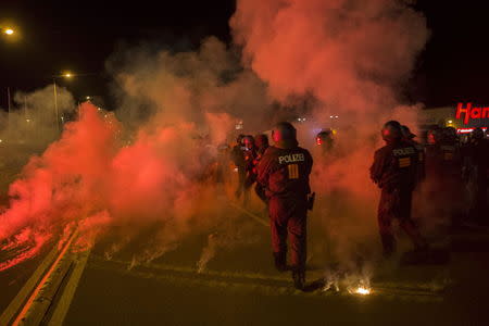 Policemen walk between flares thrown by right wing protesters who are against bringing asylum seekers to an accomodation facility in Heidenau, Germany August 22, 2015. REUTERS/Axel Schmidt
