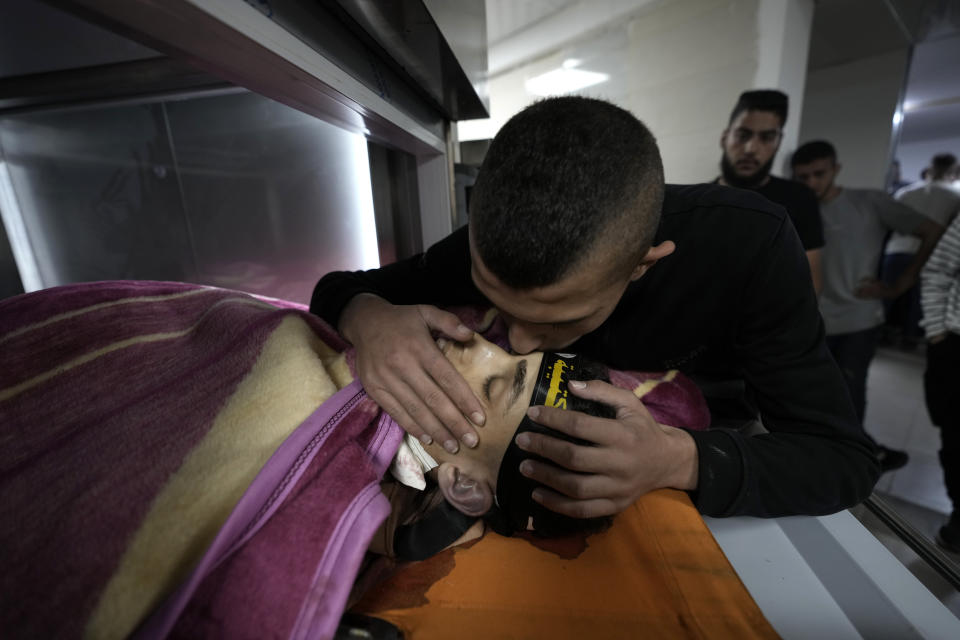 A relatives takes a last look at Ahmed Assaf, 19, wearing the headband of Islamic Jihad, one of two Palestinians killed by Israeli forces in Qabatiya, near the West Bank city of Jenin, Wednesday, May 10, 2023. The Israeli military said that Palestinian gunmen opened fire at troops in the Palestinian town of Qabatiya in the northern West Bank during an army raid. Troops returned fire, killing the two men, and confiscated their firearms, it said. (AP Photo/Majdi Mohammed)