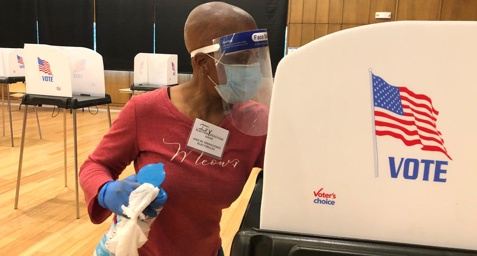 Ivy West, an elections judge, cleaning a booth after someone voted at the Silver Spring Civic Building in Silver Spring, Maryland.